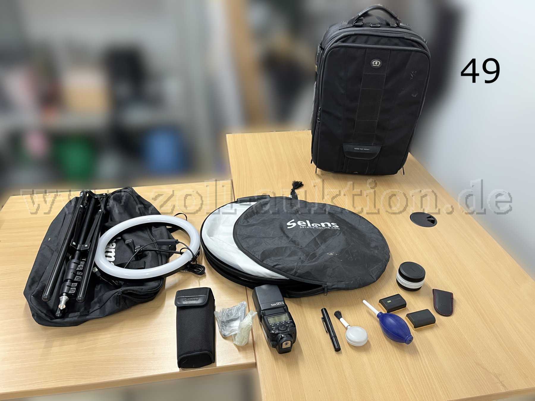 Übersicht Mischposten, von links nach rechts: Ringlicht mit Stativ und Tasche, Falt-Diffuser mit Tasche, Blitzaufsatz, Reinigungszubehör, Akkus, Fernauslöser, Objektivaufsatz, Rollkoffer