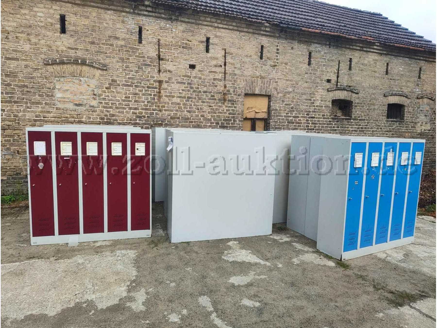 Graue Spinde mit Türen in Dunkelrot und Blau, versehen mit Schildern zur Beschriftung von Namen, Nummern und Ähnlichem.