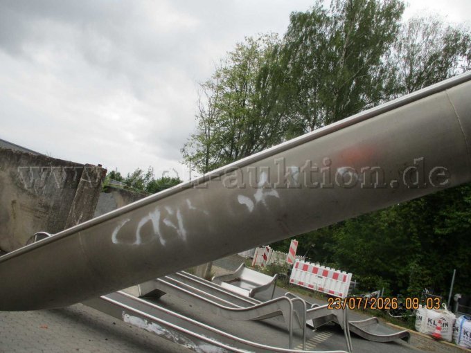 Nahaufnahme der weißen Schmierereien (Graffiti) an der Unterseite der Rutschenwange.