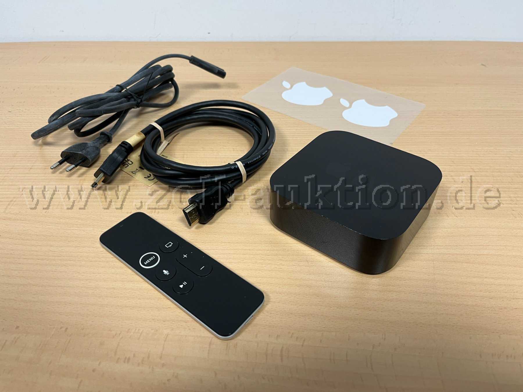 Apple TV mit Fernbedienung, Kabeln und Aufkleber.