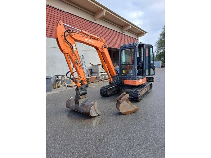 Hitachi ZX40U-2
Bagger Ansicht von rechts vorne mit montiertem Grabenräumlöffel sowie danebenliegendem Tieflöffel, geöffnete Kabinentüre