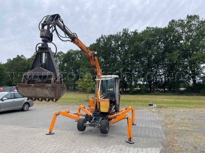 oranger Bagger mit ausgebreiteten Stützbeinen und großem Greifarm