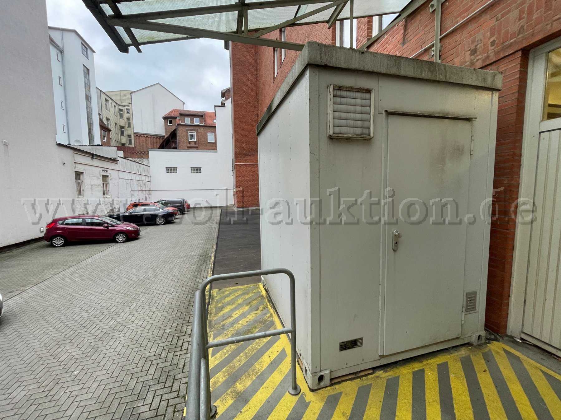 Auf dem Bild ist die Front eines Containers mit einer Eingangstür, Lüftungsklappe, Typenschild zu sehen