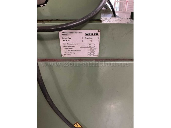 Typenschild mit Hersteller (Weiler), Maschinen-Typ (Praktikus) und Maschinen-Nummer (75). Zudem sind Farbabblätterungen und Verschmutzungen mit Betriebsmitteln zu erkennen.