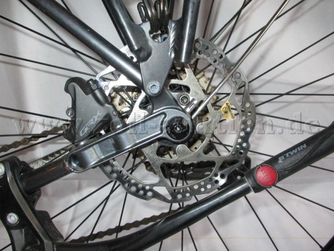 Teilansicht Hinterrad mit Scheibenbremse, GRX Bremssattel und Teilansicht vom Fahrradständer