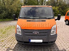 Der orangefarbene Ford Transit Tourneo als Dreisitzer ist auf diesem Bild frontal fotografiert.