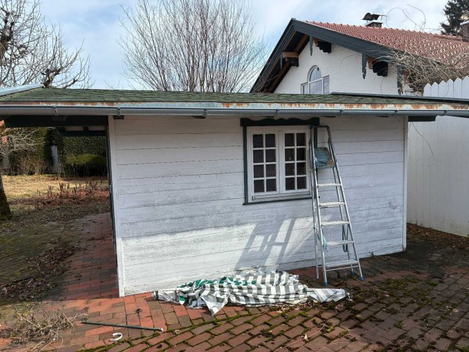 Zu sehen ist die linke Seitenansicht der Hütte mit einem Fenster und witterungsbedingten Abnutzungen.