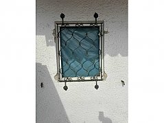 Zu sehen ist das Fenstergitter mit witterungsbedingten Abnutzungen.