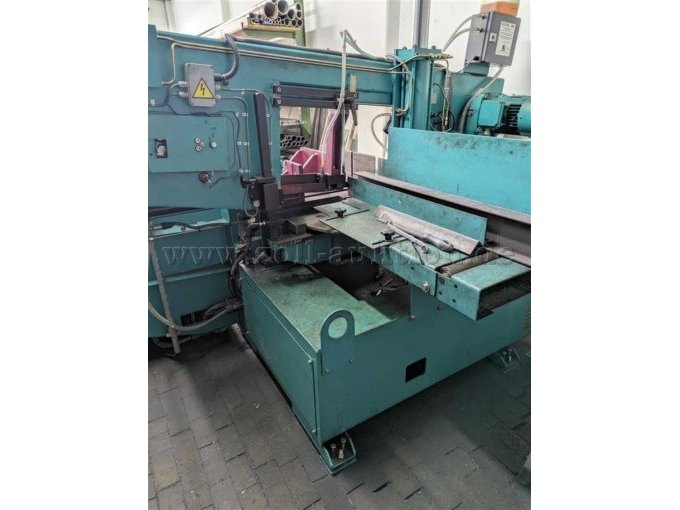 Industrielle Bandsägemaschine. Zentral im Bild befindet sich der Sägebereich mit Materialauflage.Rechts ist ein Rollentransporttisch zur Materialzufuhr integriert.