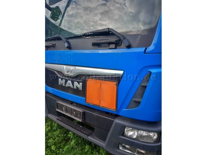 Blauer MAN TGL LKW von vorne mit einer orangenen Hinweistafel zum aufklappen.
