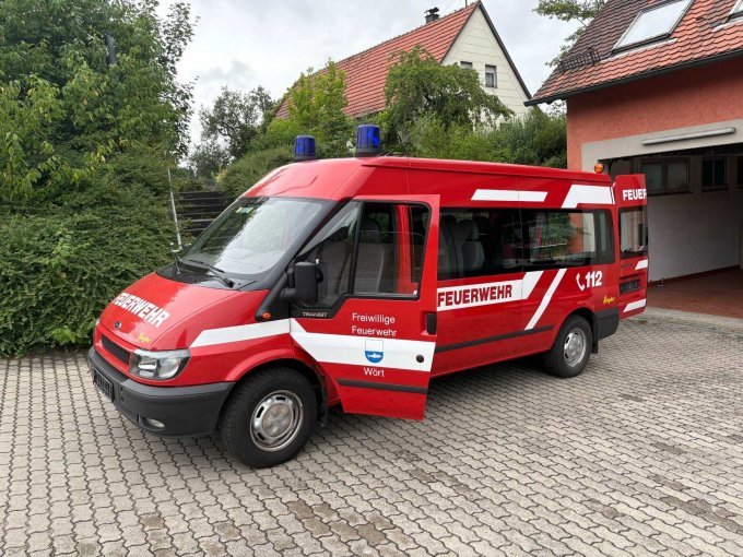 Seitenansicht des Mannschaftstransportwagens auf der Fahrerseite mit Blaulichtanlage auf dem Fahrzeugdach sowie dem Wappen der Gemeinde Wört und der Aufschrift „Feuerwehr“.