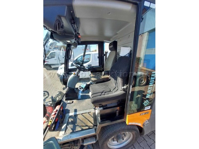 Blick in die Fahrerkabine von der Beifahrerseite; zu sehen ist Verschleiß an Kunststoffteilen, Lankrad und Sitzen