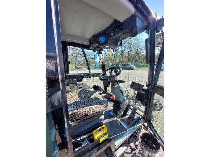 Blick in die Fahrerkabine von der Fahrerseite; zu sehen ist Verschleiß an Kunststoffteilen, Lenkrad und Sitzen