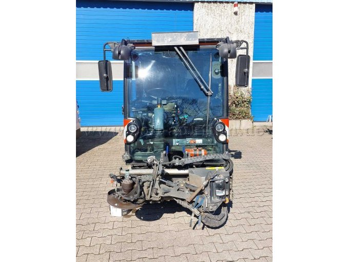 Frontansicht mit Blick auf den Anbau für den dritten Besen (Besenteller nicht angebaut); Anbaugerät weißt adaptiv zum Fahrzeug Gebrauchsspuren in Form von Kratzern, Lackschäden und etwas Korrosion auf