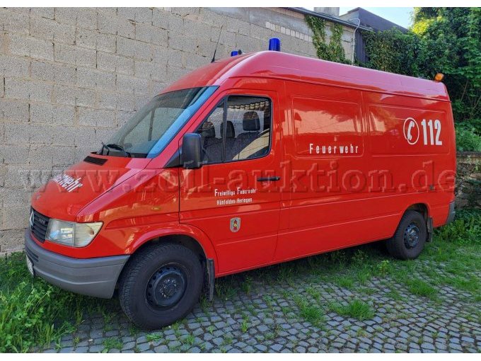 Gesamtansicht auf ein rotes Feuerwehrfahrzeug mit Blaulicht und der Beschriftung "Freiwillige Feuerwehr Hünfelden" und der Notrufnummer "112"
