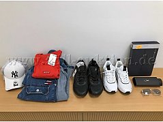 Übersicht Mischposten: Zwei Caps (untereinander gestapelt), Jeansjacke, T-Shirt, schwarze Sneaker, weiße Sneaker, Socken in Schachtel, Sonnenbrille mit Etui