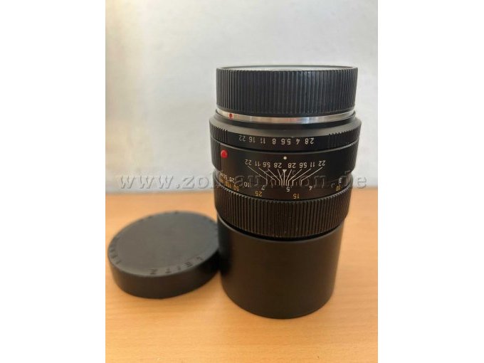 Objektiv steht aufrecht, Objektivdeckel liegt daneben, Beschriftung ist erkennbar