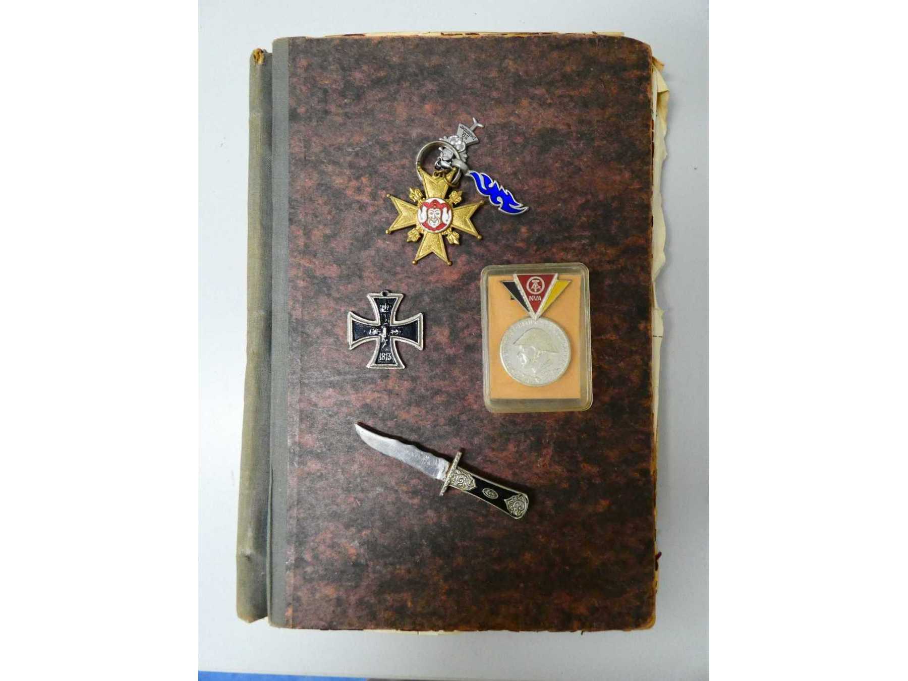 Sammlung Militärorden_ Gesamtansicht auf eisernes Kreuz, NVA-Medaille, arabisches Messer, Narrenkreuz und Notizbuch