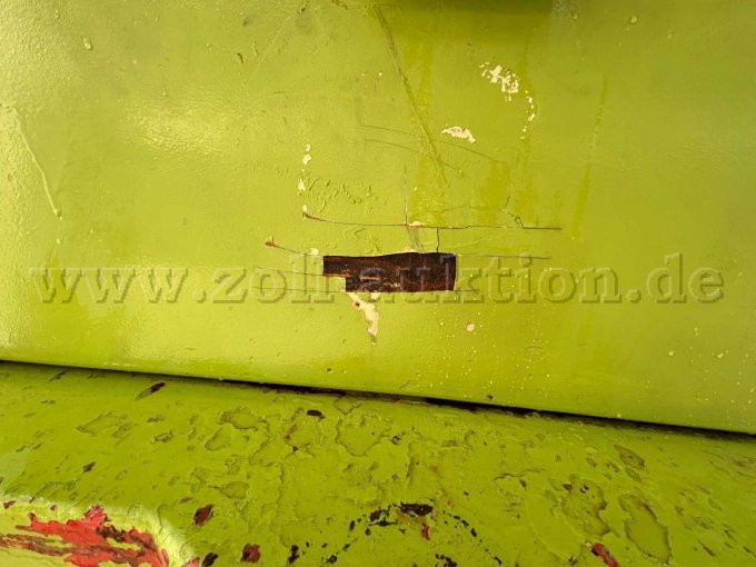 Lackabplatzer hinten an der Motorhaube in der Mitte des Radladers
