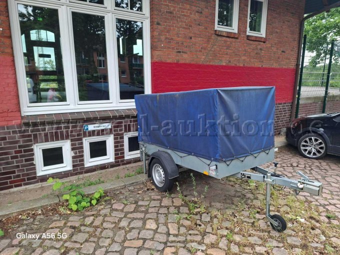Pkw-Anhänger der Marke STEMA mit blauem Planenaufbau in Seitenansicht. Pkw-Anhänger der Marke STEMA mit blauem Planenaufbau in Seitenansicht.
