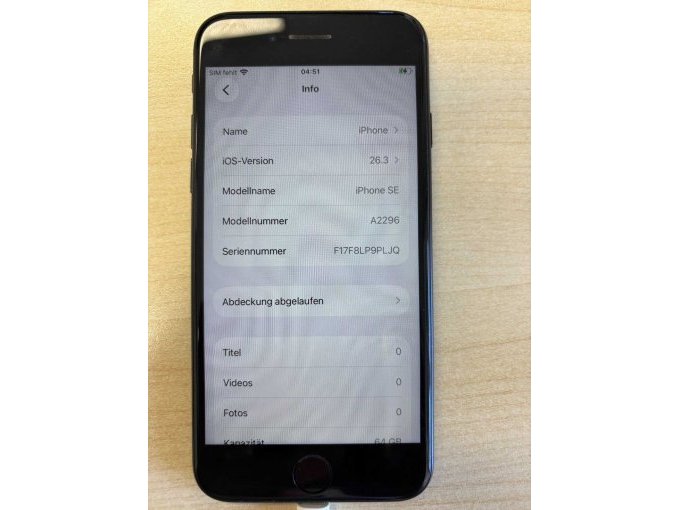iPhone aus der Sicht von oben, während des Ladevorgangs über Stecker, mit Info-Ansicht zum Gerät. Angezeigt werden iOS-Version, Modellname, Modellnummer und Seriennummer