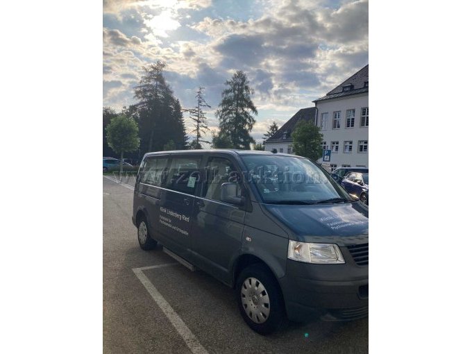Ansicht Fahrzeug von schräg vorne und rechte Seite. An der rechten unteren Seite befindet sich die eingefahrene Trittstufe. Radzierblenden in silber. Schiebetüre rechts mit großen Glasfenster.