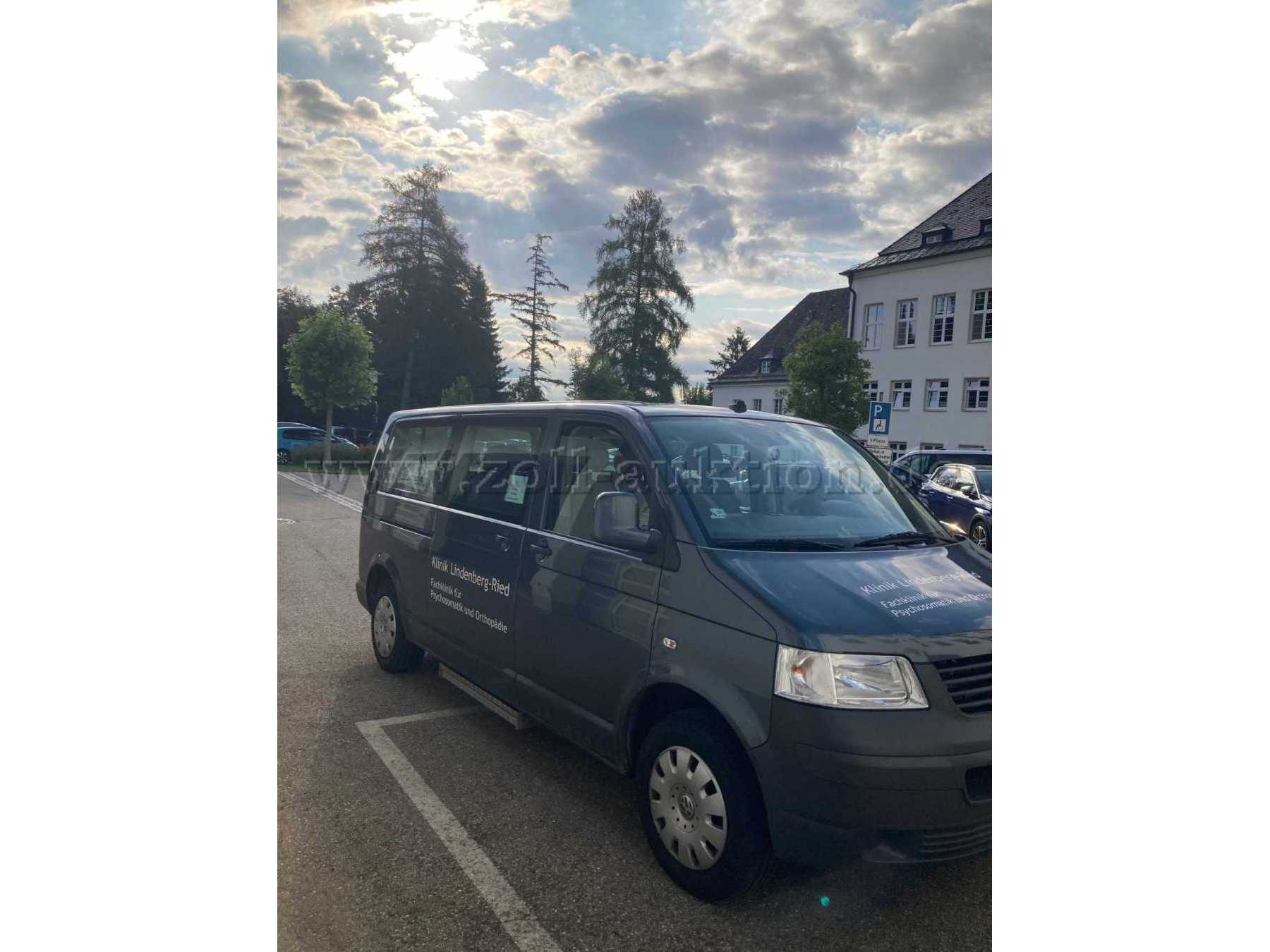 Ansicht Fahrzeug von schräg vorne und rechte Seite. An der rechten unteren Seite befindet sich die eingefahrene Trittstufe. Radzierblenden in silber. Schiebetüre rechts mit großen Glasfenster.