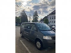 Ansicht Fahrzeug von schräg vorne und rechte Seite. An der rechten unteren Seite befindet sich die eingefahrene Trittstufe. Radzierblenden in silber. Schiebetüre rechts mit großen Glasfenster.