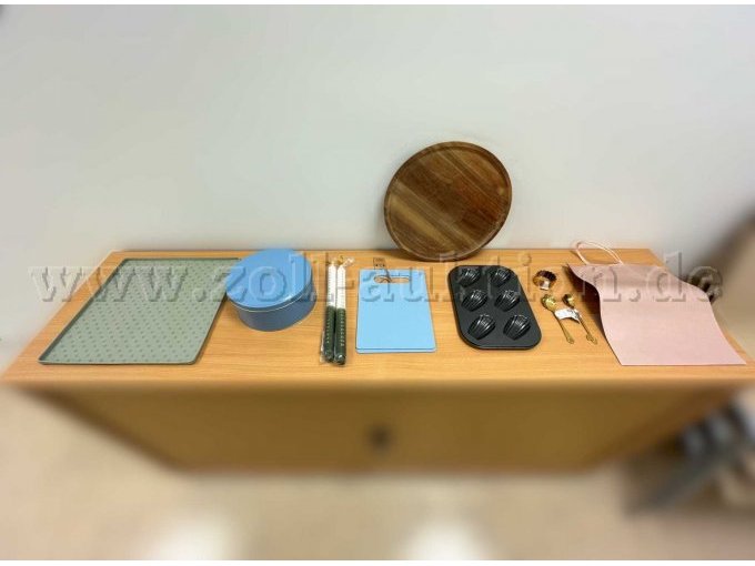 Von Søstrene Grene: Gummi-Abtropf-Matte, Keksdose aus Blech, zwei Kerzen, zwei Schneidebretter aus Kunststoff, ein Holz-Tablett, eine Küchleinform, Löffel, Keksausstecher und Papier-Geschenktüten