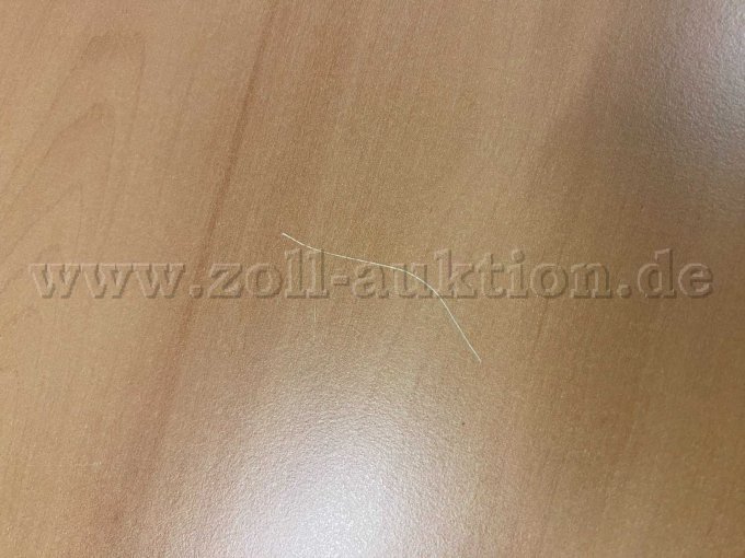 Auf der Tischplatte ist ein größerer Kratzer sichtbar.