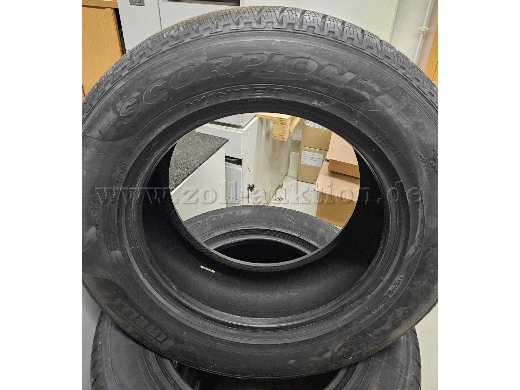 Das Bild zeigt einen Stapel schwarzer Autoreifen. Der vorderste Reifen steht aufrecht und man kann die Aufschrift "Scorpion Winter" und "Pirelli", was auf Winterreifen der Marke "Pirelli" hinweist.